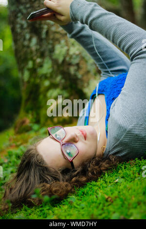 Portrait Of Teenage Girl Lying On Field At Park