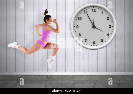 Composite image of fit brunette running against grey room Stock Photo