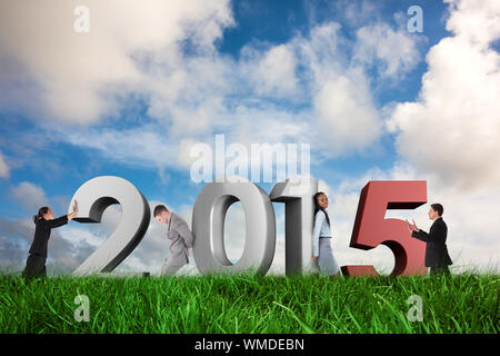 Businessman in suit pushing against green grass under blue sky Stock Photo