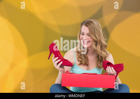 Blonde woman discovering shoes in a gift box against blurry yellow christmas light circles Stock Photo