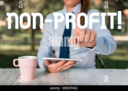 Text sign showing NonProfit. Business photo text not making or conducted primarily to make profit organization Female business person sitting by table Stock Photo