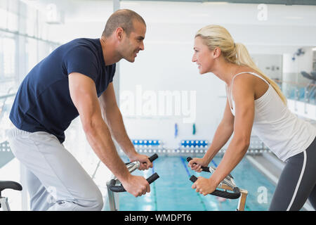 Side view of smiling fit couple working on exercise bikes at the gym Stock Photo