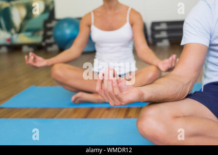 Close up of a sporty young couple sitting in lotus posture at fitness studio Stock Photo