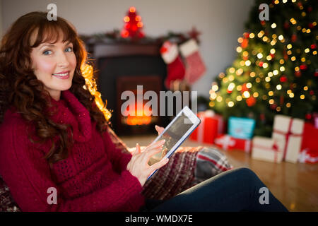 Smiling redhead using tablet at christmas at home in the living room Stock Photo