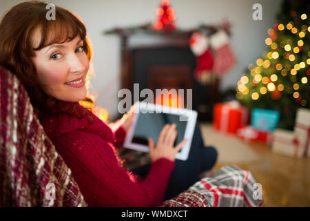 Beauty redhead using tablet at christmas at home in the living room Stock Photo