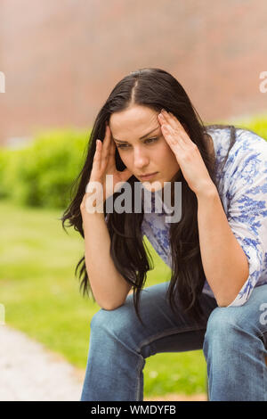 Casual brunette suffering from headache in the park Stock Photo