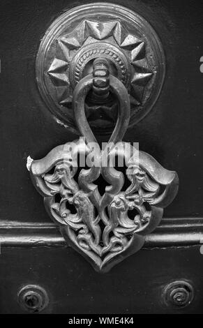 Old copper door knob with Arabic pattern on black wooden gate. Izmir, Turkey. Black and white, retro style photo Stock Photo