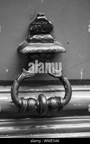 Old rusted knocker on green wooden door in Paris, France. Black and white, retro style photo Stock Photo