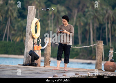 Asian man concentrate to controls and monitors drone on the sea jetty. Stock Photo