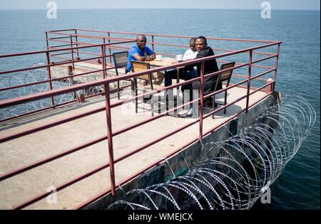 05 September 2019, Congo, Goma: UN employees are sitting on a barbed wire bar in a cafe on the premises of the UN peace mission 'Monusco'. Here Foreign Minister Maas informed himself about the work of the peace mission in the northeast of the Democratic Republic of Congo. Photo: Kay Nietfeld/dpa Stock Photo