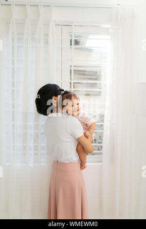 Portrait of happy vietnamese mother hugging with her cute little daughter at home Stock Photo