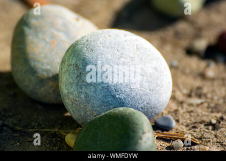 Beautiful, soft, pebbles photographed on a pebbled beach in Greece. A small olive branch can be seen between the little stones. Stock Photo
