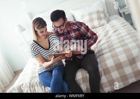 Happy couple using digital tablet in bedroom Stock Photo