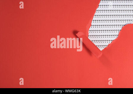 red paper teared revealing question mark on white paper. concept of FAQ, Q&A, search, riddle and information Stock Photo