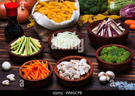 Dried noodles (Penne Rigate) and Chopped Vegetables in Juliana: Zucchini, Onions, Eggplant, Carrots, Mushrooms and Broccoli. Stock Photo
