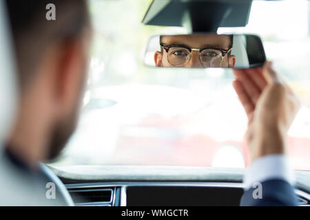 Businessman fixing rear view mirror before driving his car Stock Photo
