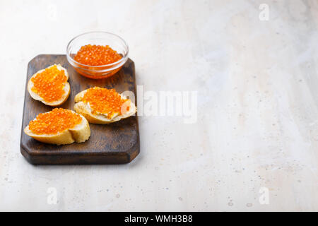 Sandwiches with red caviar and butter in plate on wooden table. Top view Stock Photo