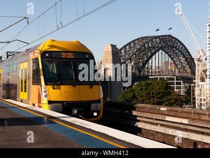 Sydney Harbour Bridge with Train approaching Milsons Point Railway Station. Sunny morning. Blue Sky. Stock Photo