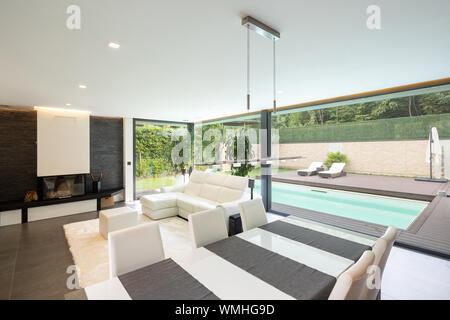 Modern living room overlooking the garden and swimming pool. Nobody inside Stock Photo