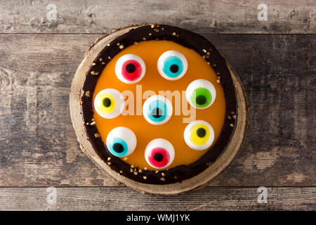 Halloween cake with candy eyes decoration on wooden table. Top view. Stock Photo