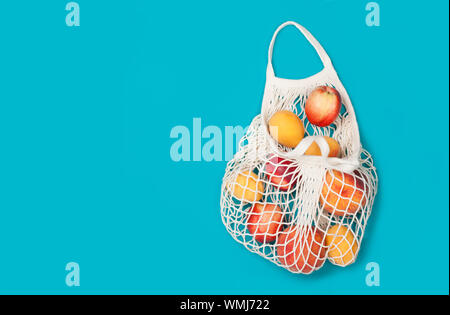 Juicy ripe peaches and apricots in eco bag on a blue background. Zero waste concept, plastic-free, eco-friendly shopping, vegan Stock Photo