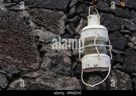 Antique white metal lamp, hanging on a stone wall Stock Photo