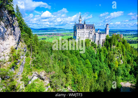 Neuschwanstein Castle in beautiful mountain scenery of Alps- in the background you can see the Lake Forggensee - near Fuessen, Bavaria, Germany Stock Photo