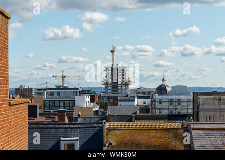 Across rooftops, large cranes working on a building site in Worthing, West Sussex. Stock Photo