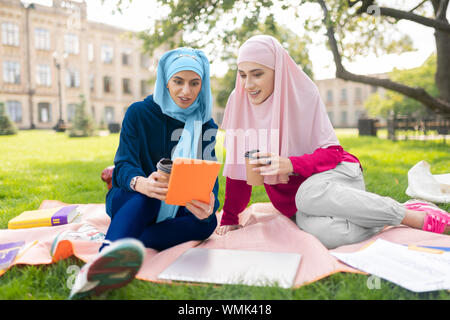 Muslim students watching video on tablet and drinking coffee Stock Photo