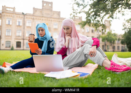 Muslim female young students preparing presentation in the park Stock Photo