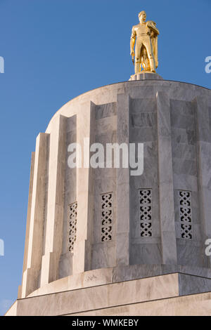 The Oregon Pioneer, also known as the Gold Man, statue is an eight-and-a-half ton bronze statue with gold leaf finish that sits atop the Oregon State Stock Photo