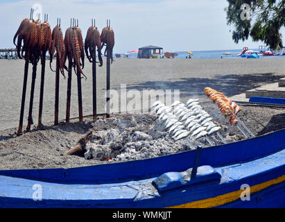 Octopus being cooked on hot embers at popular seafood restaurant El Penon in Salobrena beach resort on the Costa Tropical, Granada, Spain. Stock Photo