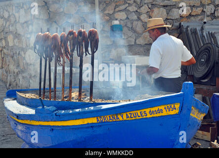 Octopus being cooked on hot embers at popular seafood restaurant El Penon in Salobrena beach resort on the Costa Tropical, Granada, Spain. Stock Photo