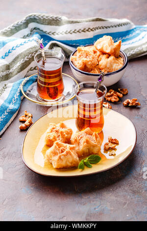 Middle Eastern or Arabic tea with mint in a traditional glass cup and Turkish delight Baklava. Ramadan kareem. Eid mubarak. Islamic holidays decoratio Stock Photo