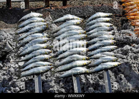 Sardines and other fish being cooked on hot embers at popular seafood restaurant El Peñon in beach resort of Salobreña on the Costa Tropical, Spain. Stock Photo