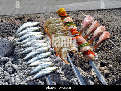 Sardines and other fish being cooked on hot embers at popular seafood restaurant El Peñon in beach resort of Salobreña on the Costa Tropical, Spain. Stock Photo