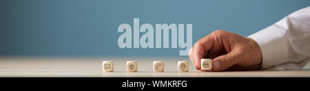 Wide view image of hand of a businessman placing wooden cubes with contact, communication and location icons in a row. Stock Photo