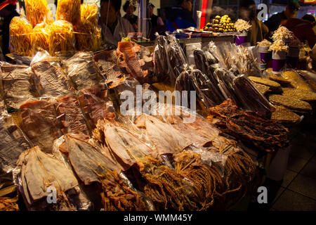 Outdoor food stall at nighttime selling dried squid and other seafood snacks. Stock Photo