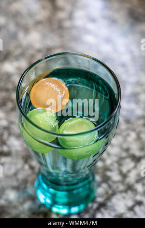 Coca Cola glass with colorful ice cube standing on a granite platform. High angle view, close up. Stock Photo