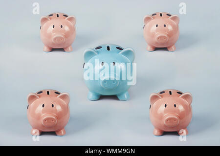 Different colored piggy bank standing out of the crowd. The uniqueness and leadership concept, individuality and difference. Finance and money saving Stock Photo