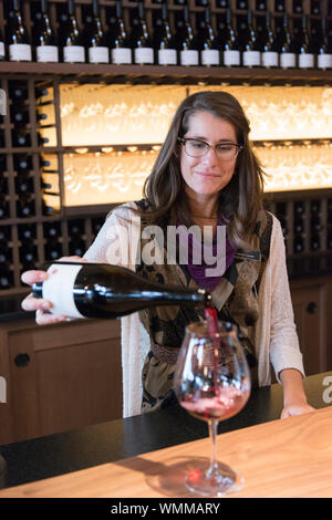 Employee Heather Daenitz (model released) pours a glass of Pinot Noir. Willamette Valley Vineyards is a well known producer of Pinot Noir and is locat Stock Photo