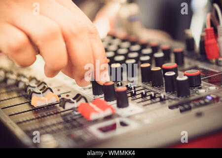 The hand over adjusting knobs on a professional audio mixer for sound mixer control. Selective focus. Stock Photo