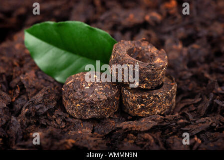 Aromatic black pu-erh tea. Fermented and compressed Leaves into bricks. Round flat disc of puer tea. Healthy drink. Stock Photo