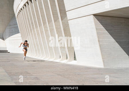 Pulled back view of female athlete running on concrete Stock Photo