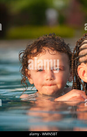 Little boy getting a piggyback ride from older girl while swimming in a pool at a resort in Cruz Bay, St. John, USVI