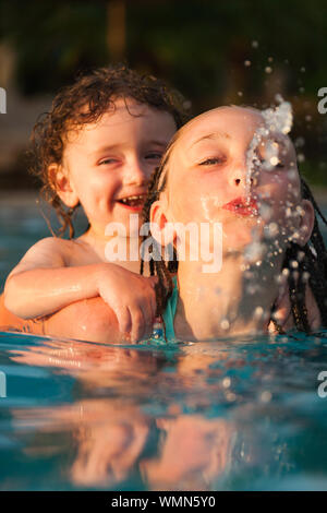 Little boy getting a piggyback ride from older girl while swimming in a pool at a resort in Cruz Bay, St. John, USVI