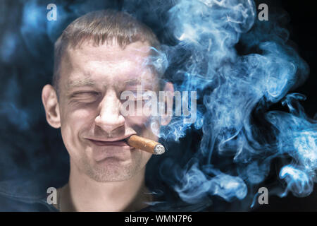 smiles with closed eyes. lots of smoke, portrait of a man close-up face. Stock Photo