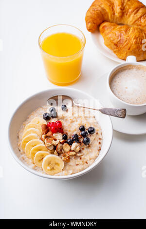 Breakfast with oatmeal with berries and nuts, coffee and orange juice