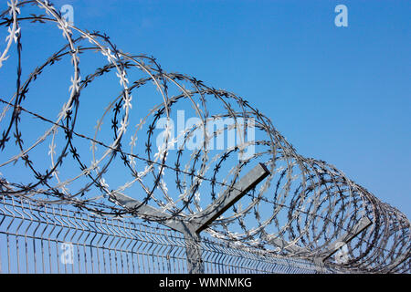 fence with barbed wire against the blue sky. Symbol of freedom of imprisonment. Stock Photo