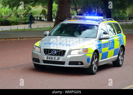A marked Police car speeds along Parliament Street with blue flashing lights, Westminster, London, UK Stock Photo